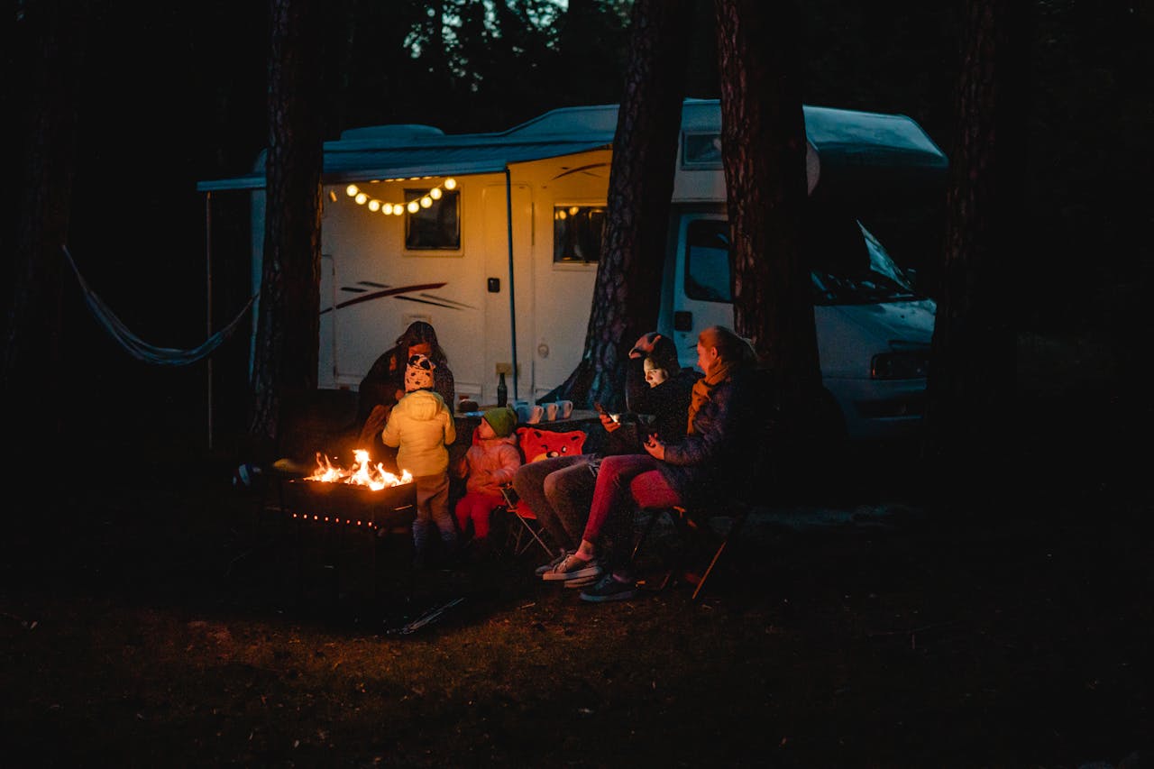 Family enjoying a warm night by the campfire beside their campervan in Lithuania.
