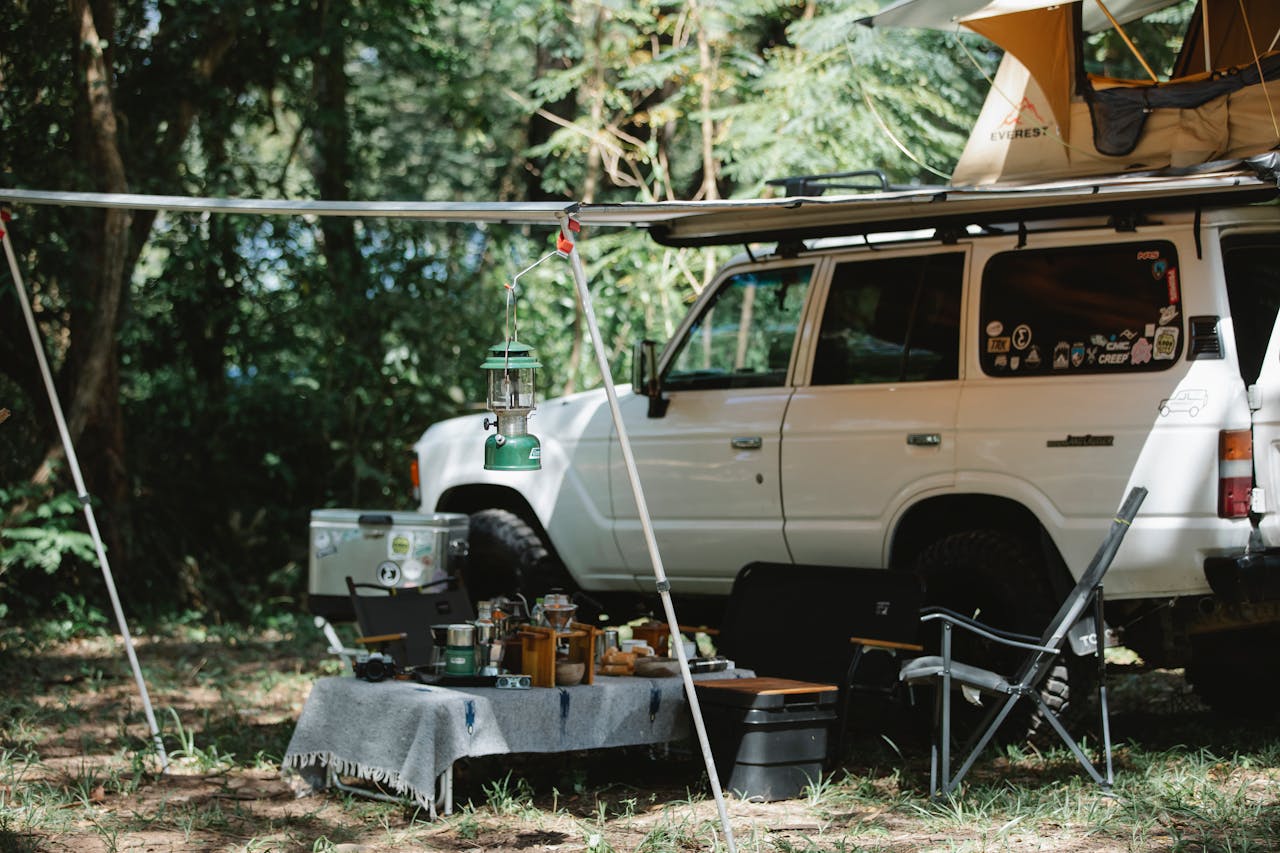 Camper offroader with roof top tent and awning camping in nature among green trees in sunny day